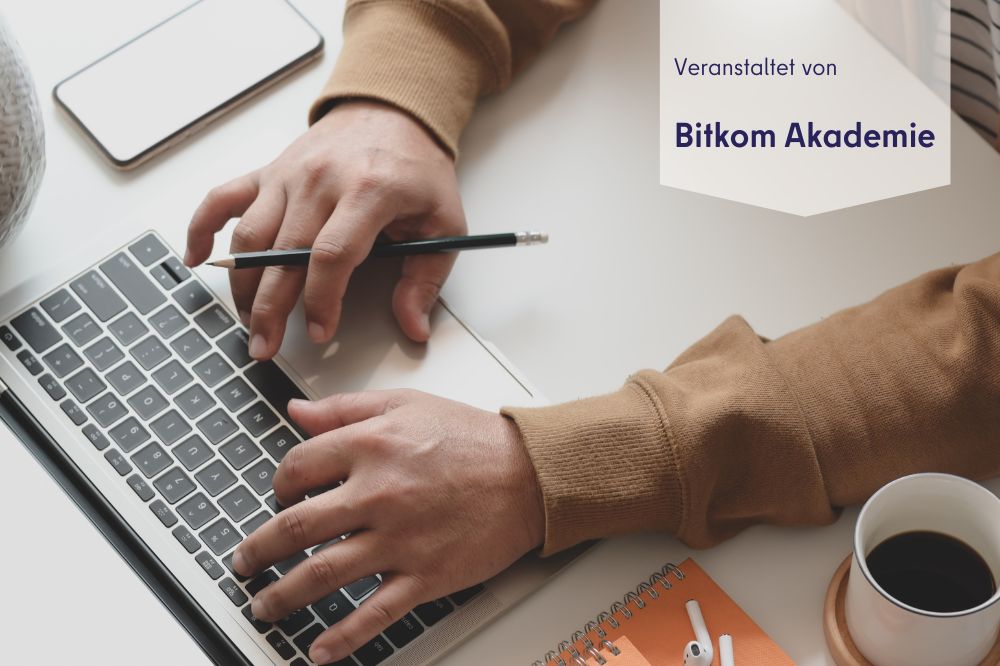Das Foto ist von oben aufgenommen. man sitzt zwei Arme bzw. Hände, die auf einer tastatur liegen. Außerdem sieht man eine Kaffeetasse.